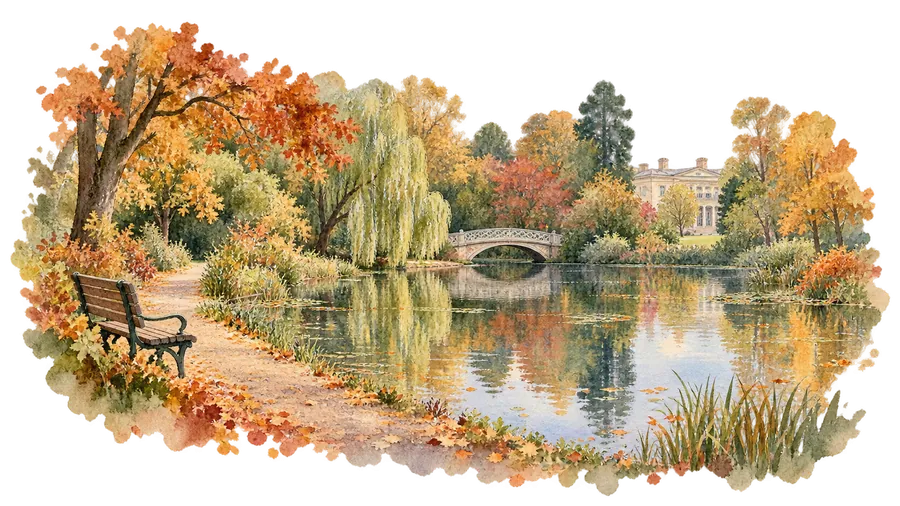 A park pond in autumn with a stone footbridge, a willow, orange and gold leaves, a wooden bench on the path and a grand house behind the trees