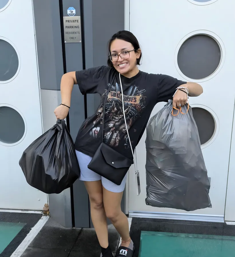 Linda, smiling, holding a full rubbish bag after a clearing session